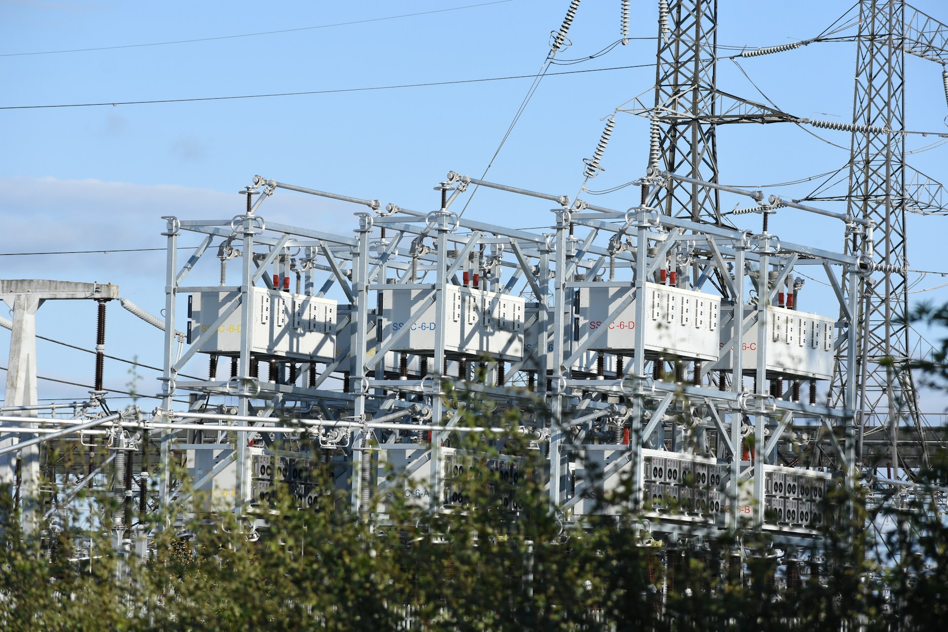 Electrical substation with transformers and transmission pylons under a blue sky
